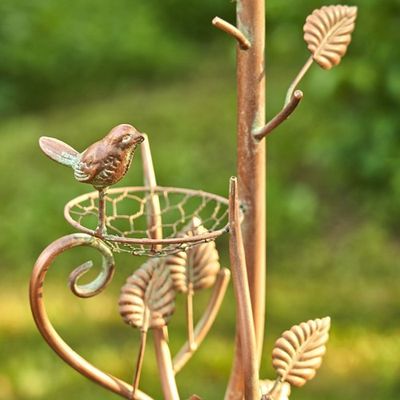 Close-up of the teapot spout and handle showing a small sculpted bird detail and weathered metallic texture.