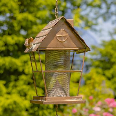 Close-up of the cottage-shaped iron feeder showing a metal bird and mushroom accents.
