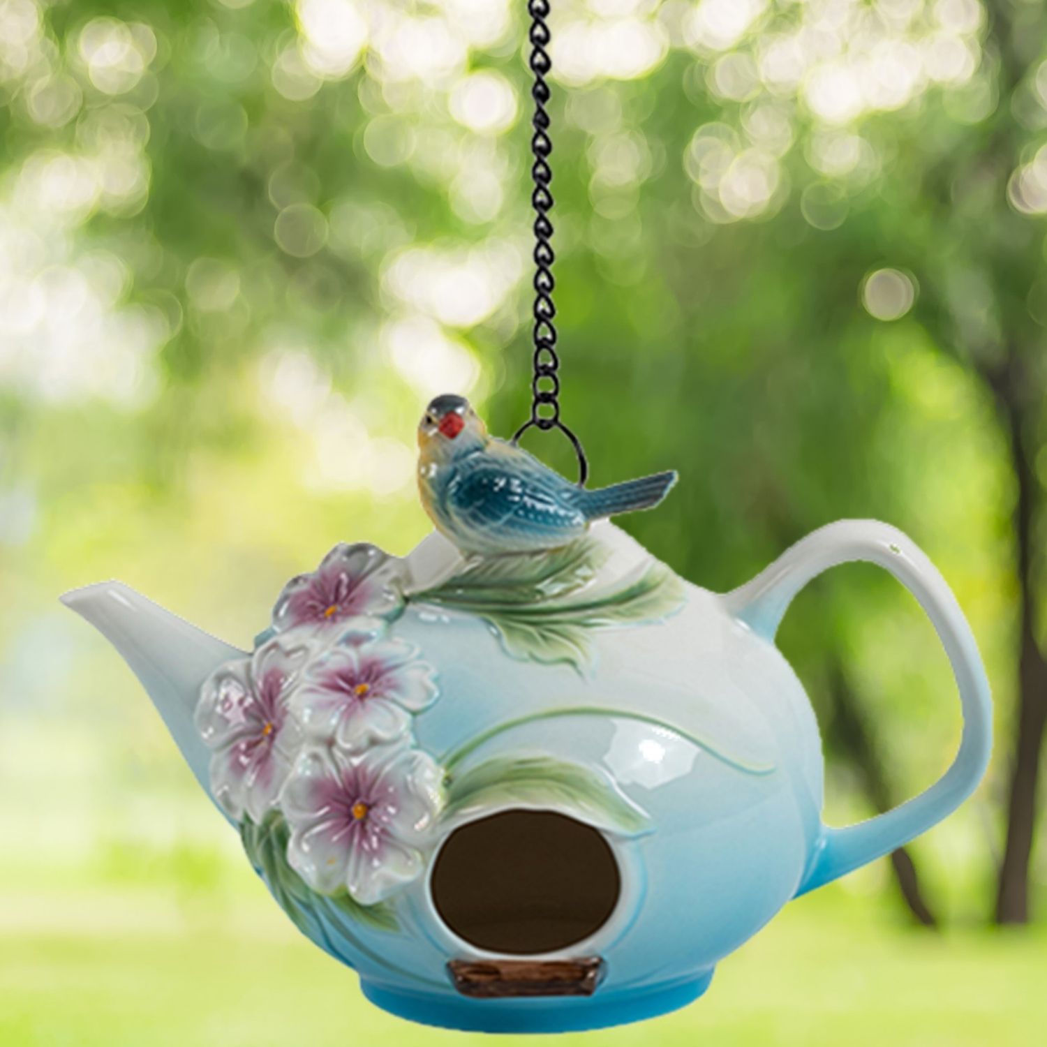 Front view of the teapot birdhouse highlighting the round entry hole and painted pink flowers.