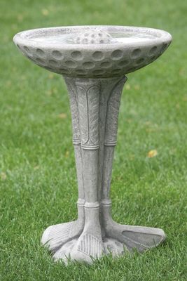 The white stone bird bath displayed outdoors on green grass, highlighting its textured basin and architectural base.
