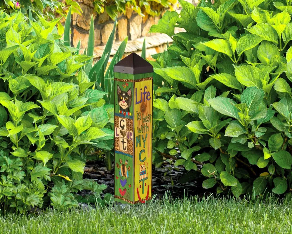 20-inch Lessons from My Cat garden art pole installed outdoors among lush green foliage.