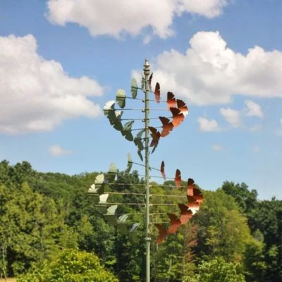 Copper and verde ginkgo leaf wind spinner with helix design on tall green garden stake displayed outdoors.
