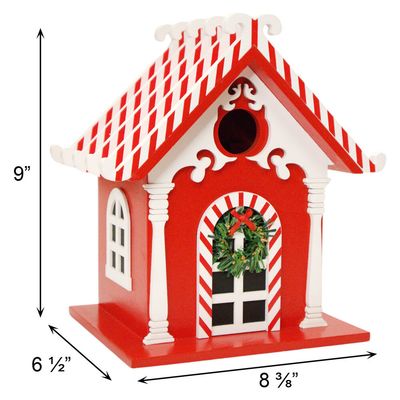 White birdhouse with red candy cane pillars, a green wreath, and a red shingled roof with white snow-like trim.