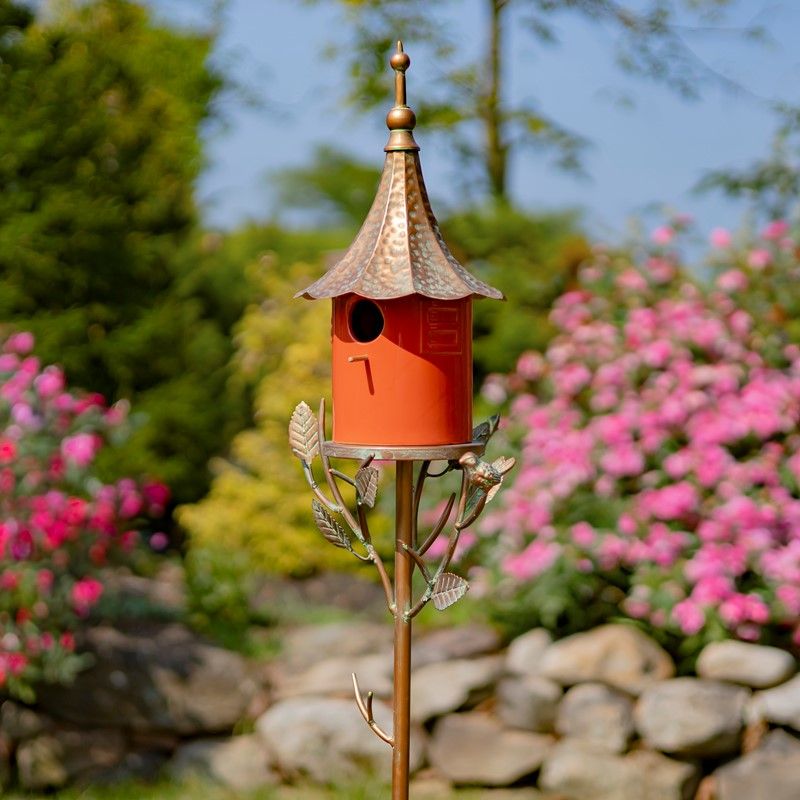Front view of the Amsterdam Birdhouse Stake featuring a vibrant, glossy orange porcelain house with a textured antique copper