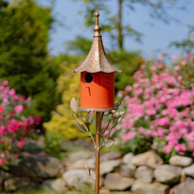 Front view of the Amsterdam Birdhouse Stake featuring a vibrant, glossy orange porcelain house with a textured antique copper