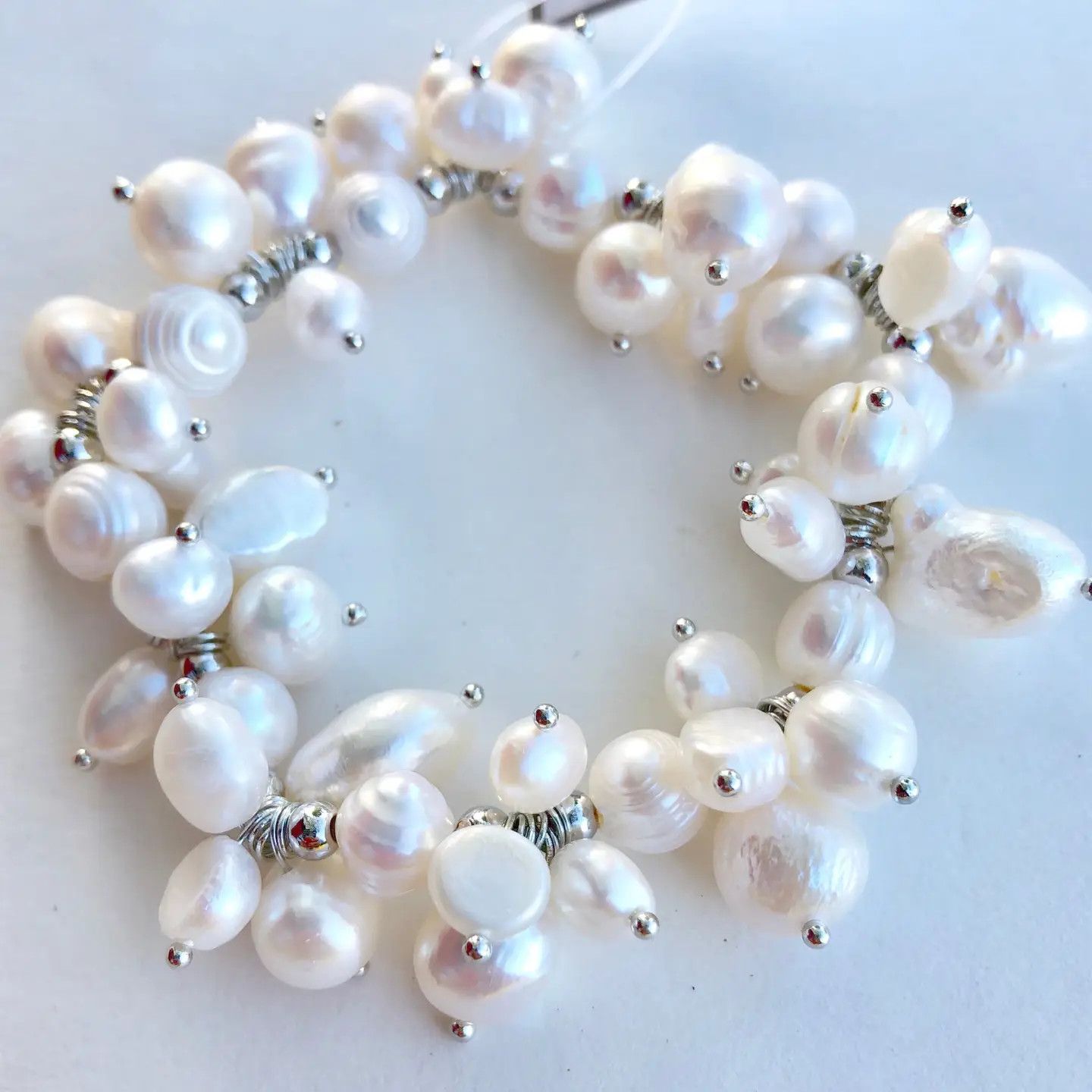 White freshwater pearl cluster stretch bracelet displayed on a light surface showing multiple glossy natural freshwater pearl