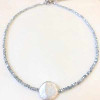 A delicate handmade necklace featuring icy frost blue crystal beads and a luminous, flat coin pearl pendant