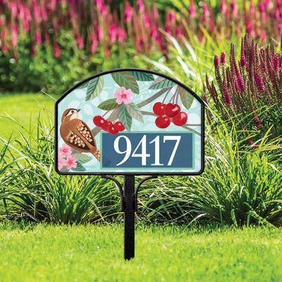 Magnetic yard sign featuring birds, cherries, and address numbers, installed in a lush garden setting.