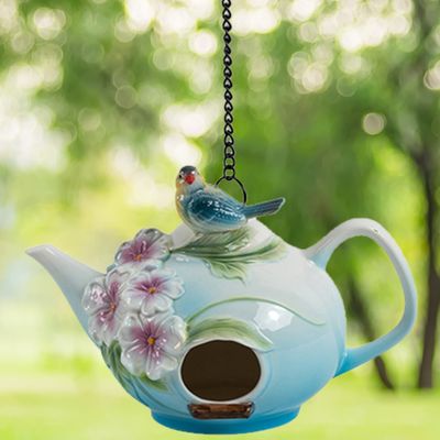 Front view of the teapot birdhouse highlighting the round entry hole and painted pink flowers.