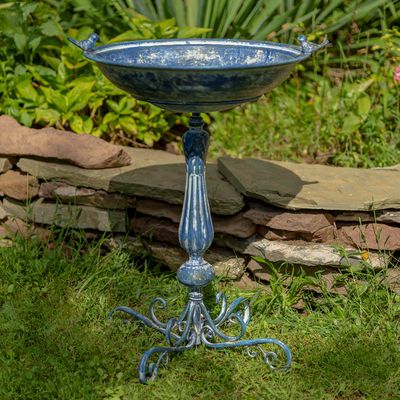 Antique blue ornate pedestal birdbath with a wide basin and two small bird figures on the rim.