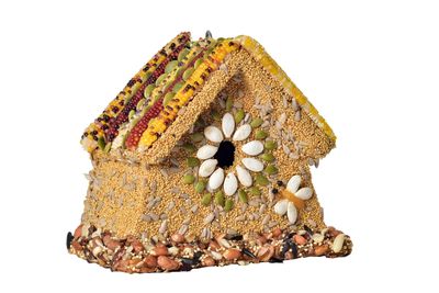 The Rustic Wren Edible Birdhouse featuring a wooden cottage frame covered in a dense layer of premium birdseed, nuts