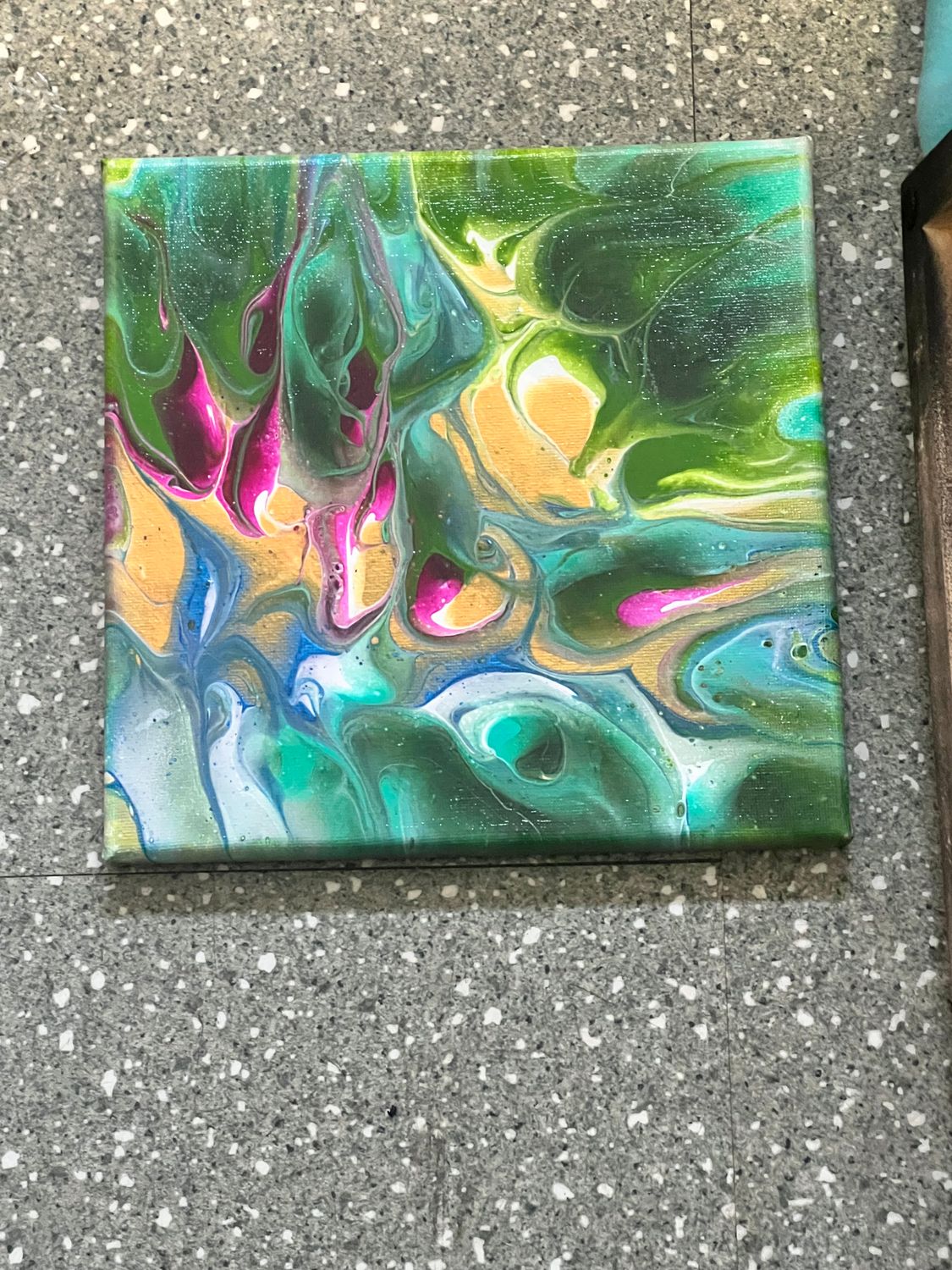 An 8x8 square artwork depicting a vibrant, colorful peacock with brilliant teal, blue, and golden plumage