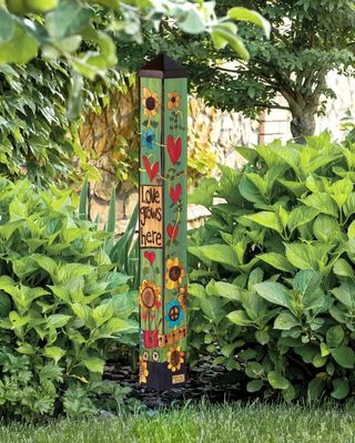 Studio M floral art pole installed in a lush garden with sun-washed colors.
