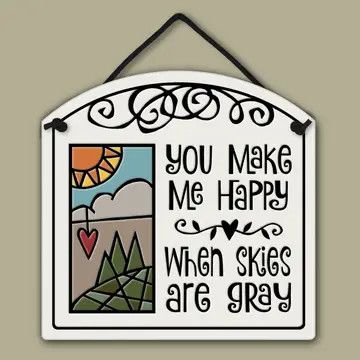 ceramic plaque reading "YOU MAKE ME HAPPY WHEN SKIES ARE GREY" with a illustration above and a dark hanging string