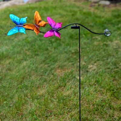 40-inch metal garden balancer stake featuring three colorful, kinetic butterflies, installed outdoors.