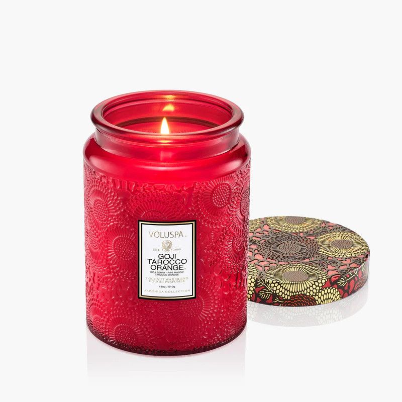 An 18oz Goji Tarocco Orange candle in a vibrant red embossed glass jar with a decorative gold lid.