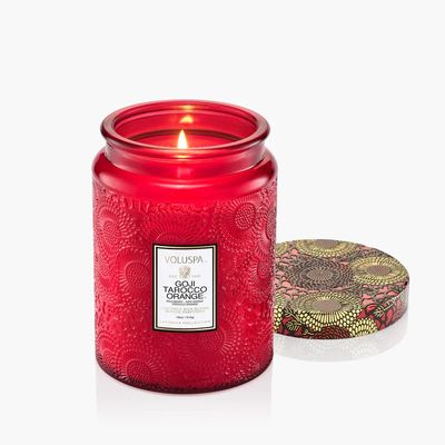 An 18oz Goji Tarocco Orange candle in a vibrant red embossed glass jar with a decorative gold lid.