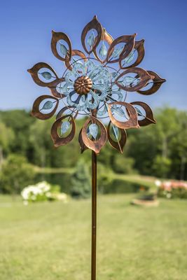Bronze and soft blue dual motion wind spinner with leaf-shaped blades mounted on tall garden stake.

