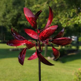 Red Windemere metal wind spinner with layered curved blades mounted on garden stake outdoors.
