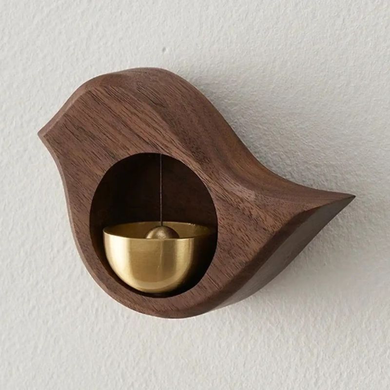 Wooden bird-shaped magnetic doorbell with brass bell in Walnut finish mounted on a light wall.