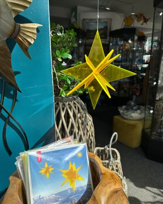 Yellow acrylic 3D hanging star ornament displayed indoors near a window.