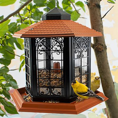hanging bird feeder with terracotta roof, ornate black panels, clear seed reservoir and large feeding tray.
