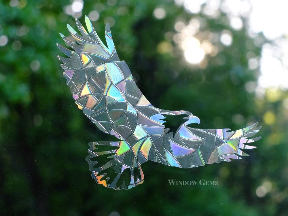 A set of rainbow prismatic eagle-shaped window cling decals displayed on a glass window catching sunlight and casting