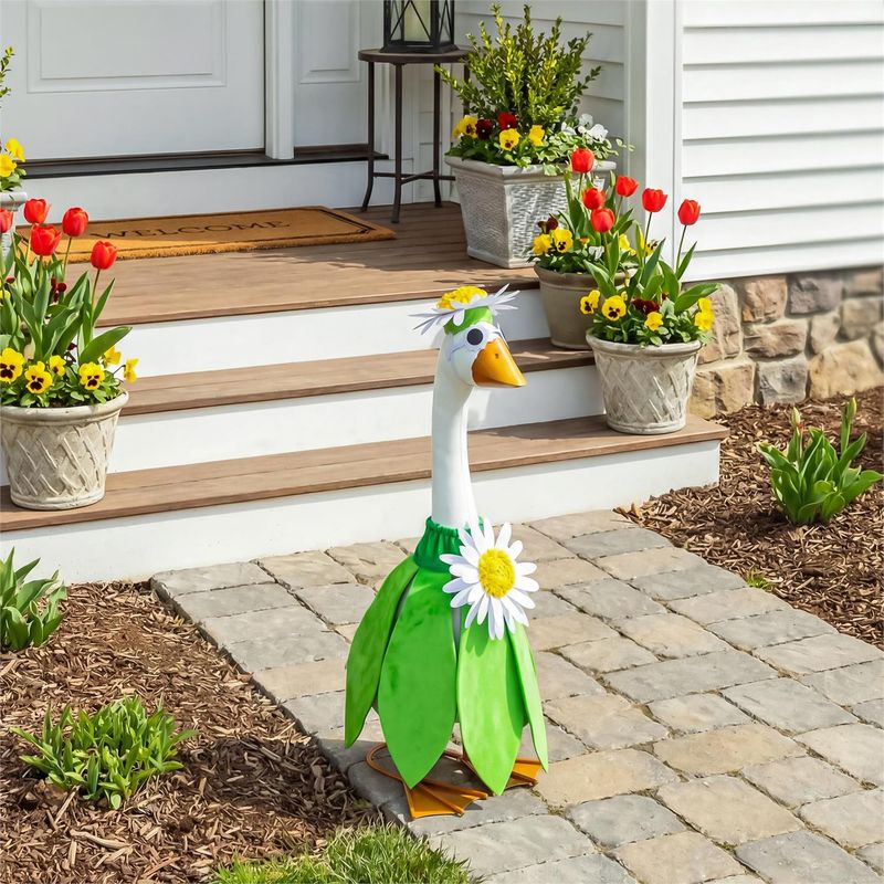 Giddy the Porch Goose wearing a green daisy outfit and flower headpiece on a stone walkway beside front steps.
