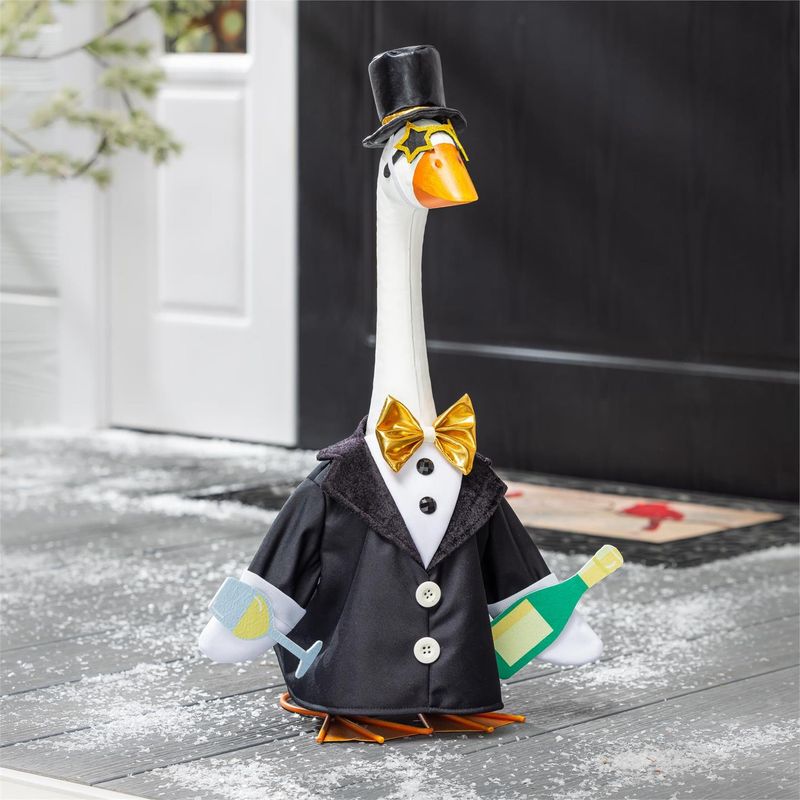 Giddy the Porch Goose wearing a black New Year suit, gold bow tie, top hat, and star-shaped glasses beside a front door.