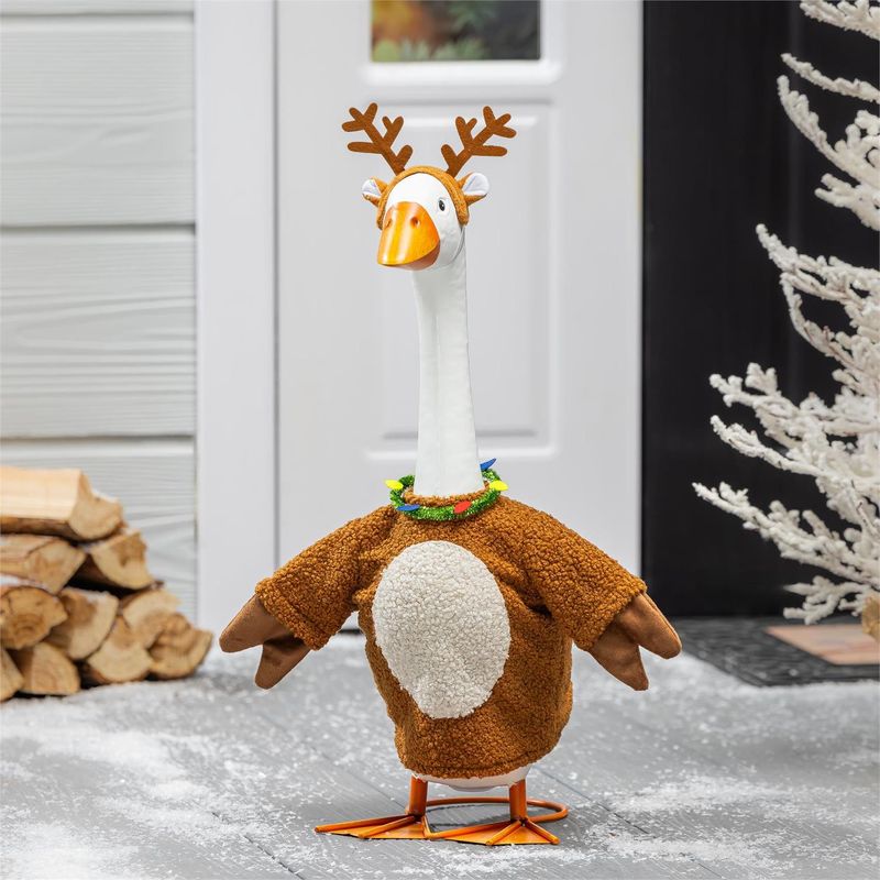 Giddy the Porch Goose wearing a brown reindeer outfit with a cream belly, antlers, and colorful light-shaped necklace beside 