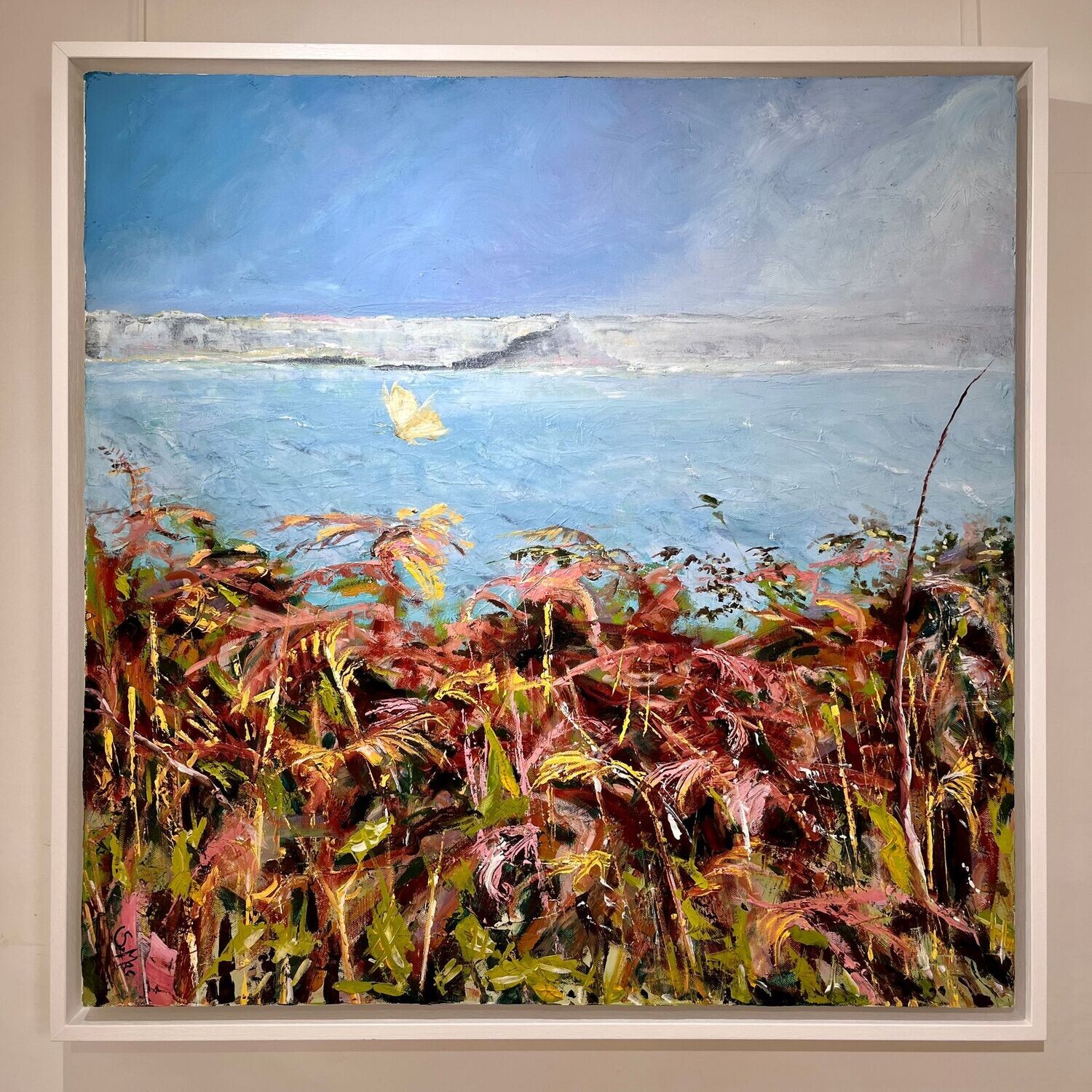 Square painting with orange / green bracken foreground. Above the light aqua sea sits a misty St Michael's Mount. Above is bright blue sky with light coming in from the top right corner. There is a Cabbage White Butterfly flying close above the bracken. Simply framed in white wood. 