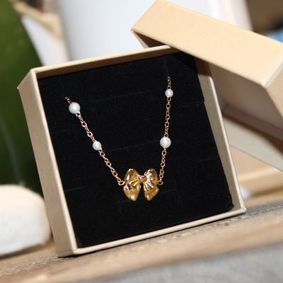 Bracelet en acier doré avec nœud papillon et perles synthétiques