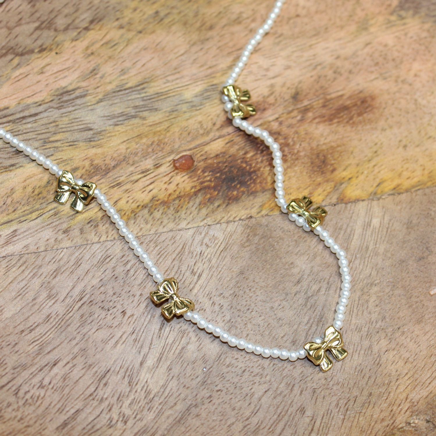 Collier ras de cou en perles synthétiques avec nœuds papillons en acier doré