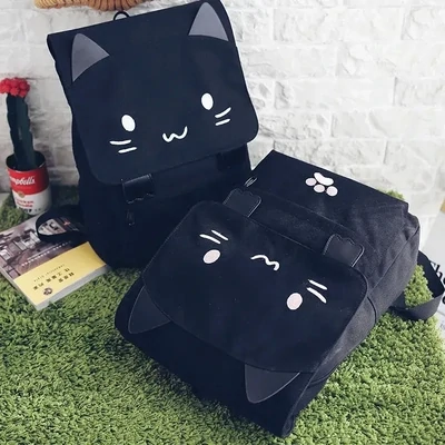 Black canvas backpack with ears, paws and the face of a cartoon cat, one laying down