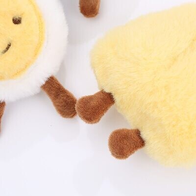 Top view zoomed in of the paws of two small cat cuddly toys in the shape of an egg and cheese
