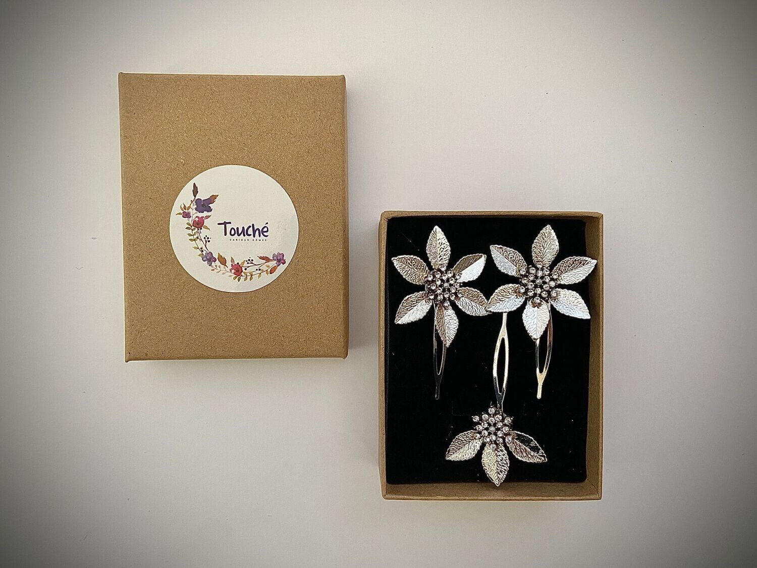 Conjunto compuesto por dos horquillas de unos 4 cm de diámetro y una horquilla de 3 x 3 cm. Cuentan con pétalos y un centro compuesto por cristales transparentes con base dorado envejecido.

Se pueden combinar con unos pendientes a conjunto del mismo tamaño que la horquilla pequeña.