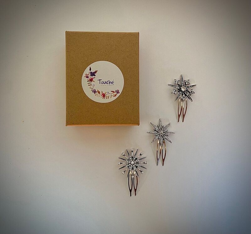 Pack compuesto por tres horquillas de estrellas diferentes en plata envejecida con cristales transparentes de unos 3 cm de diámetro cada una.