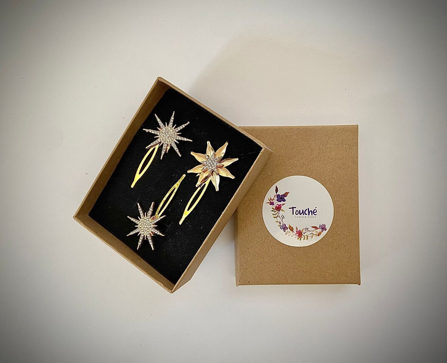 Conjunto compuesto por 3 horquillas de estrellas de unos 3 cm cada una. Dos estrellas estarían formadas por cristales y una estrella cuenta con 8 rayos dorados y una estrella central. Disponible en dorado y en plateado.

Se puede combinar con los pendientes a conjunto que estarían formados por 2 estrellas doradas y una aplicación desmontable que se puede incorporar y aportaría a la pieza unos 6 cm extra.
