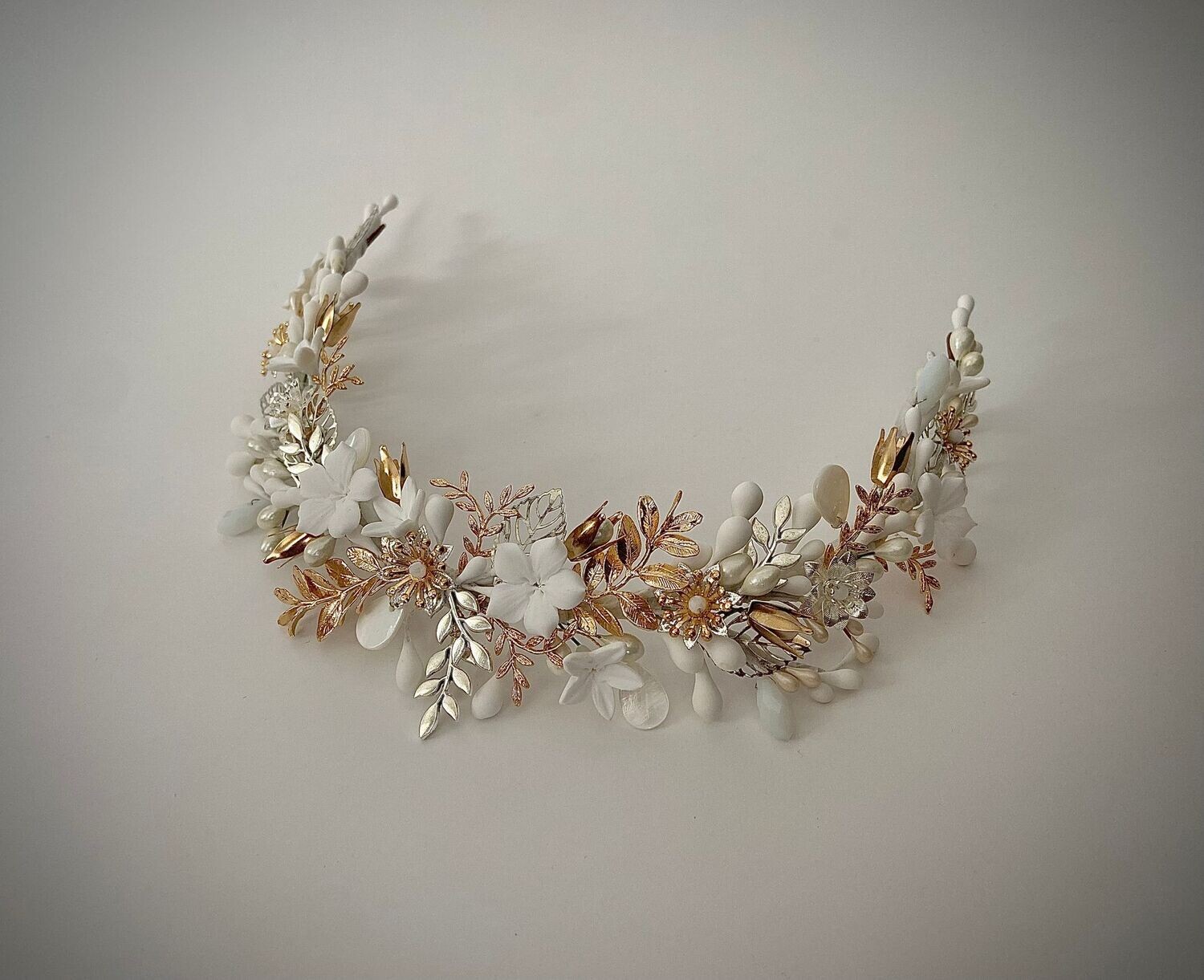 Diadema elevada compuesta por muchos pequeños detalles dentro de los que destacan las flores, las ramas, las hojas y los pistilos.

Su característica principal es la alternancia de los detalles, consiguiendo un efecto fresco y desenfadado.

Su peculiaridad es que puede utilizarse también como tocado trasero O diadema sin altura consiguiendo con una misma pieza lucir dos looks.