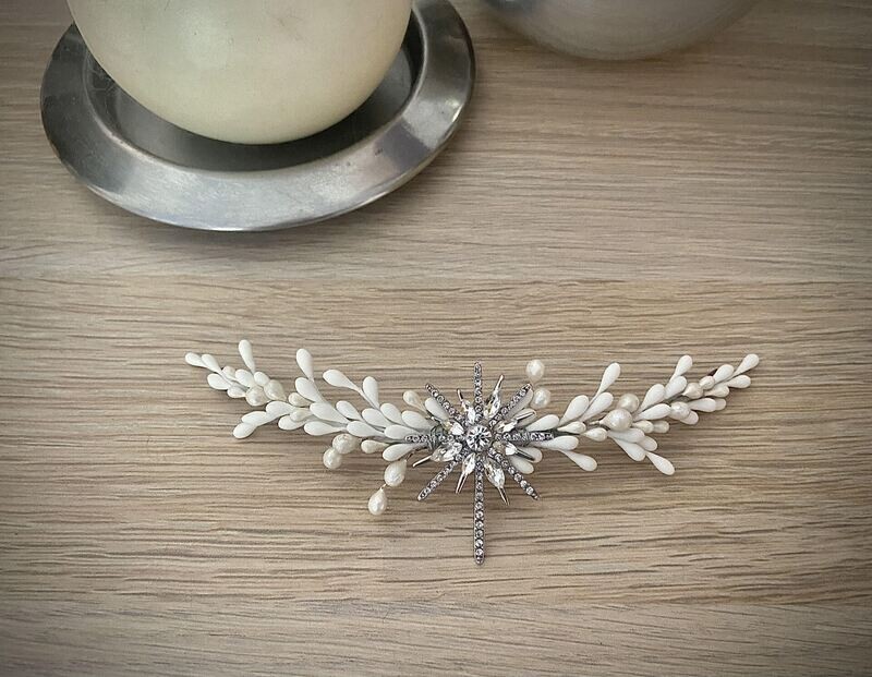 Tocado compuesto por una estrella central en plata o en dorado con pistilos alrededor en tonos blancos y nacarados.

Es un tocado de porcelana y metal sencillo que aporta un toque sofisticado al look. Es ideal si lo combinamos con las horquillas Estrella Polar.

Se pueden incluir pistilos en un color extra si quieres conjuntar con los complementos.