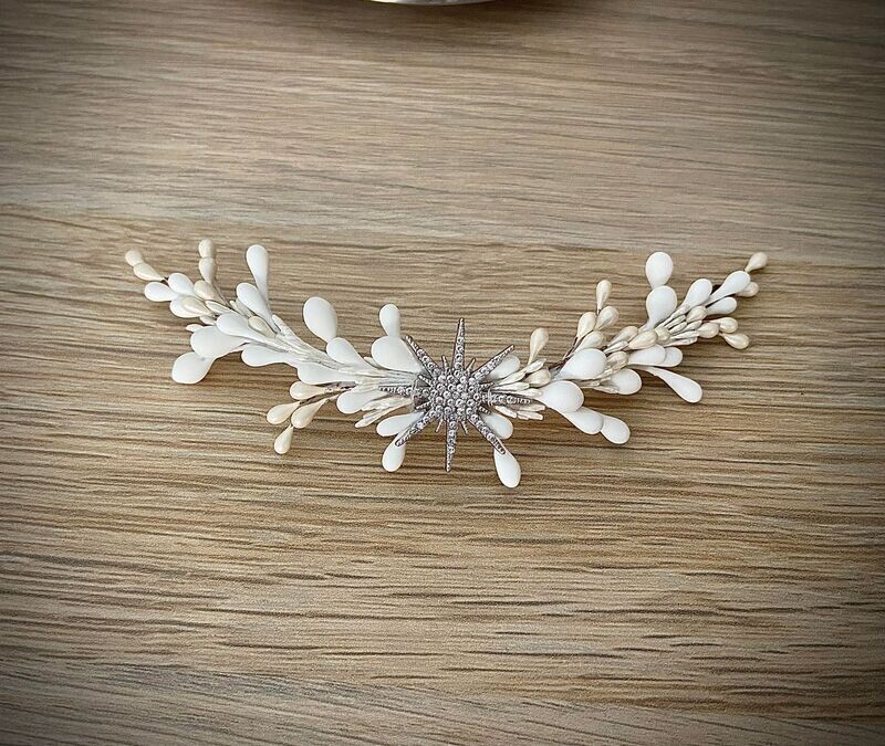 Tocado compuesto por una estrella central en plata o en dorado con pistilos alrededor en tonos blancos y nacarados. Es un tocado de porcelana y metal sencillo que aporta un toque sofisticado al look.

Se pueden incluir pistilos en un color extra si quieres conjuntar con los complementos.