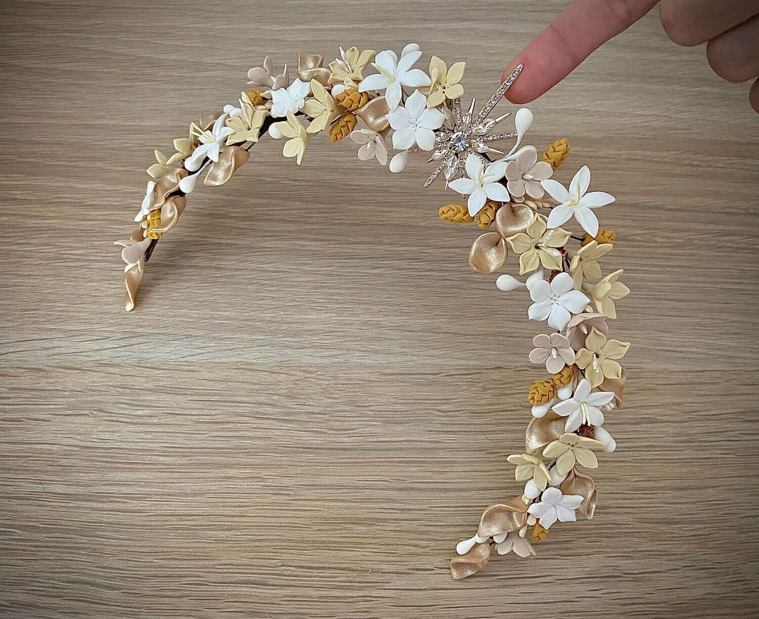 Tiara de flores de porcelana en tonos blancos, amarillos, crudos y dorados con estrella central con base dorada.