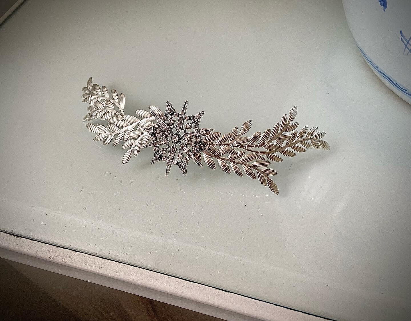 Tocado joya de unos 18 cm de longitud compuesto por 4 ramificaciones en plata y una estrella central en plata envejecida con cristales transparentes.