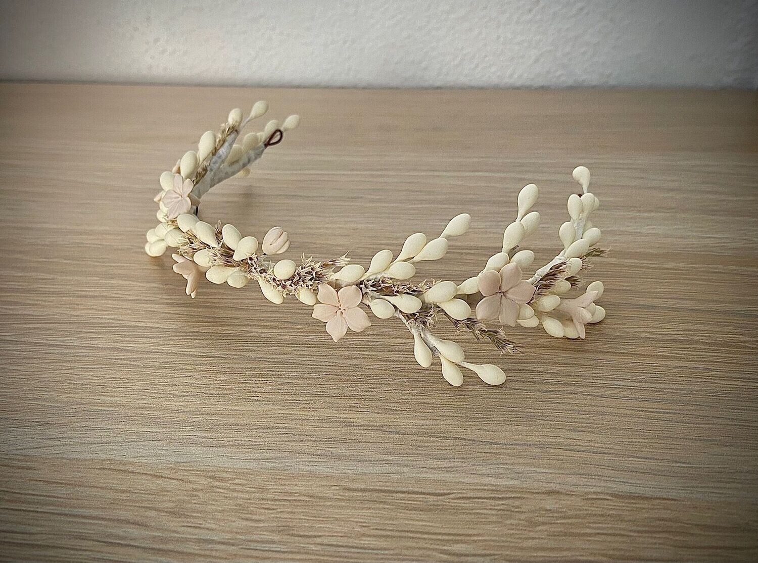 Tocado de semillas de azahar de unos 26 cm de longitud compuesto por pistilos en blanco roto y flores en tono nude con pequeñas flores preservadas.
