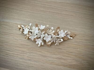 Tocado de porcelana de unos 16 cm de longitud compuesto por flores blancas, crudas y nacaradas y hojas doradas.