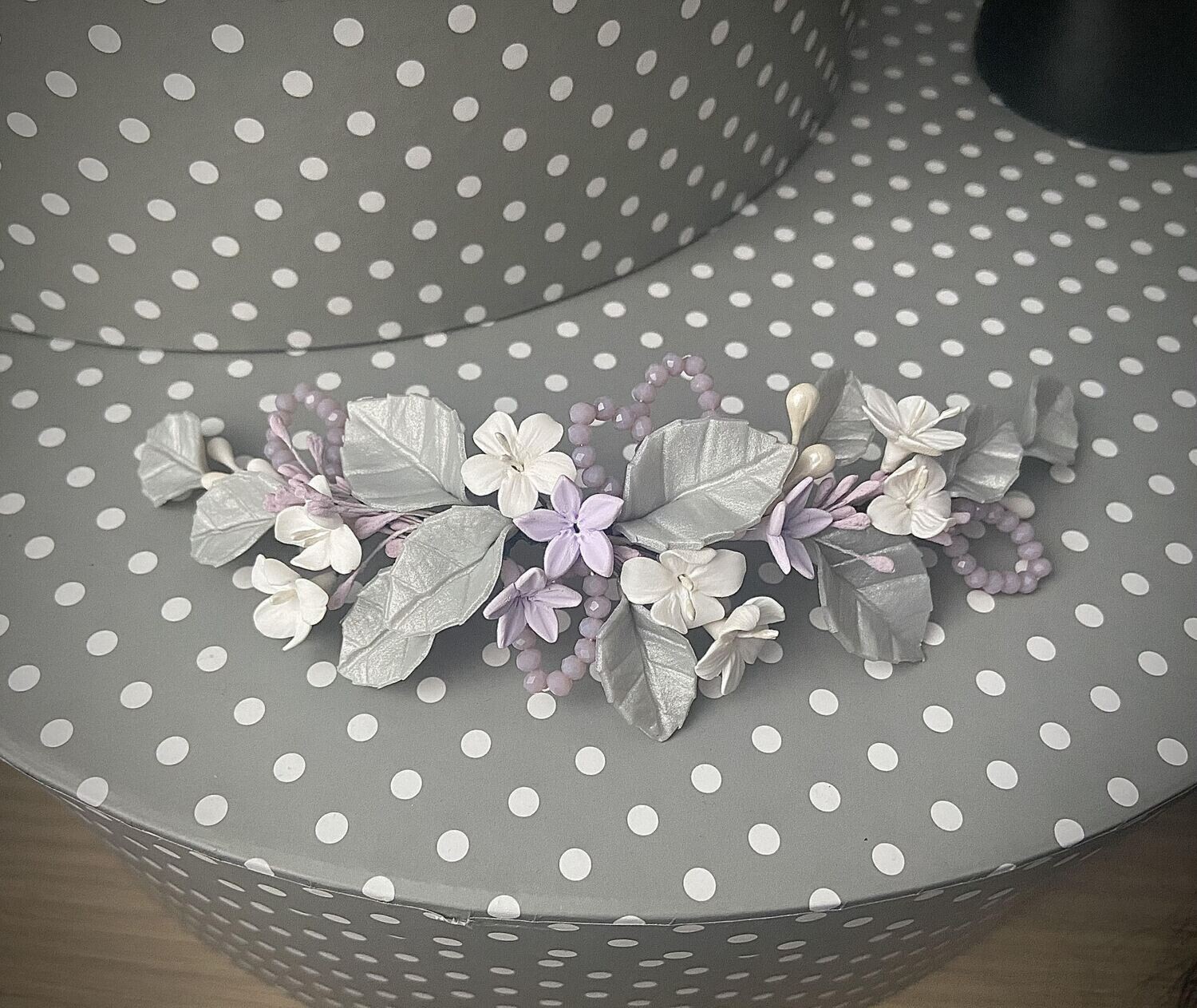 Tocado de porcelana de 18 cm compuesto por hojas plata clara, flores blancas y cristales lilas.