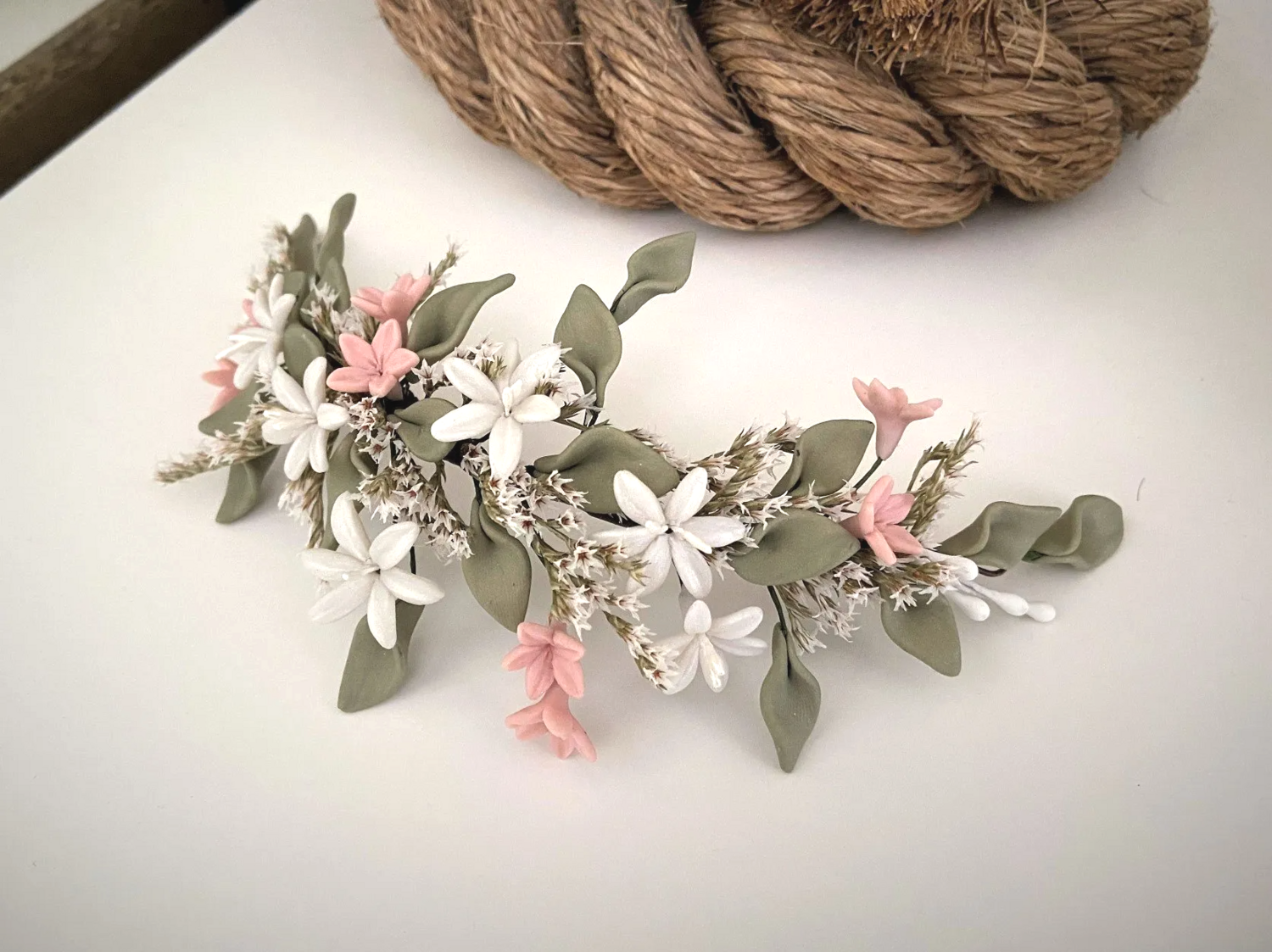 Tocado de porcelana y flor preservada de unos 24 cm de longitud en colores verde seco, crudo y rosa empolvado.