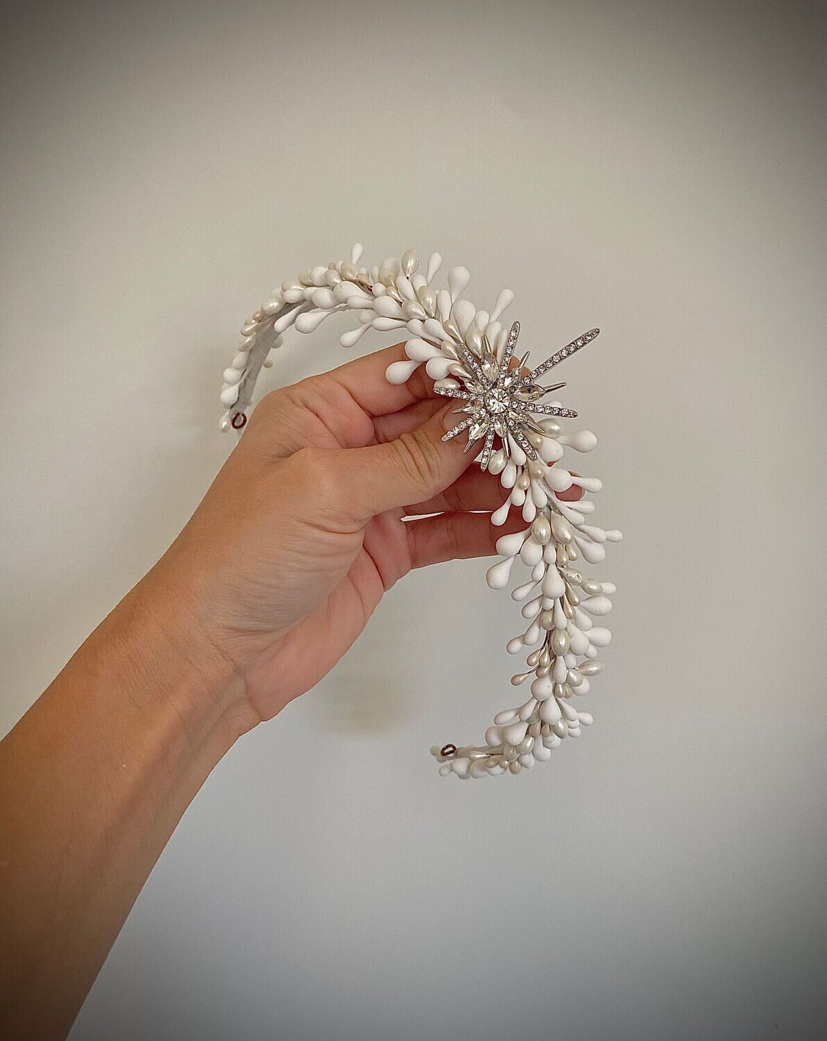 Tiara de novia compuesta por un sinfín de pistilos blancos y nacarados de unos 34 cm de longitud aproximadamente terminada con una estrella central en base dorada o plateada.

Queda preciosa si la combinas con horquillas en la parte trasera de la cabeza ya que se conseguimos equilibrar el look aportando luminosidad en la zona posterior.

Su peculiaridad es que puede utilizarse también como tocado trasero por su tamaño, consiguiendo con una misma pieza lucir dos looks.

No dudes en preguntar por personalizaciones para esta pieza incluyendo pistilos de otras tonalidades.