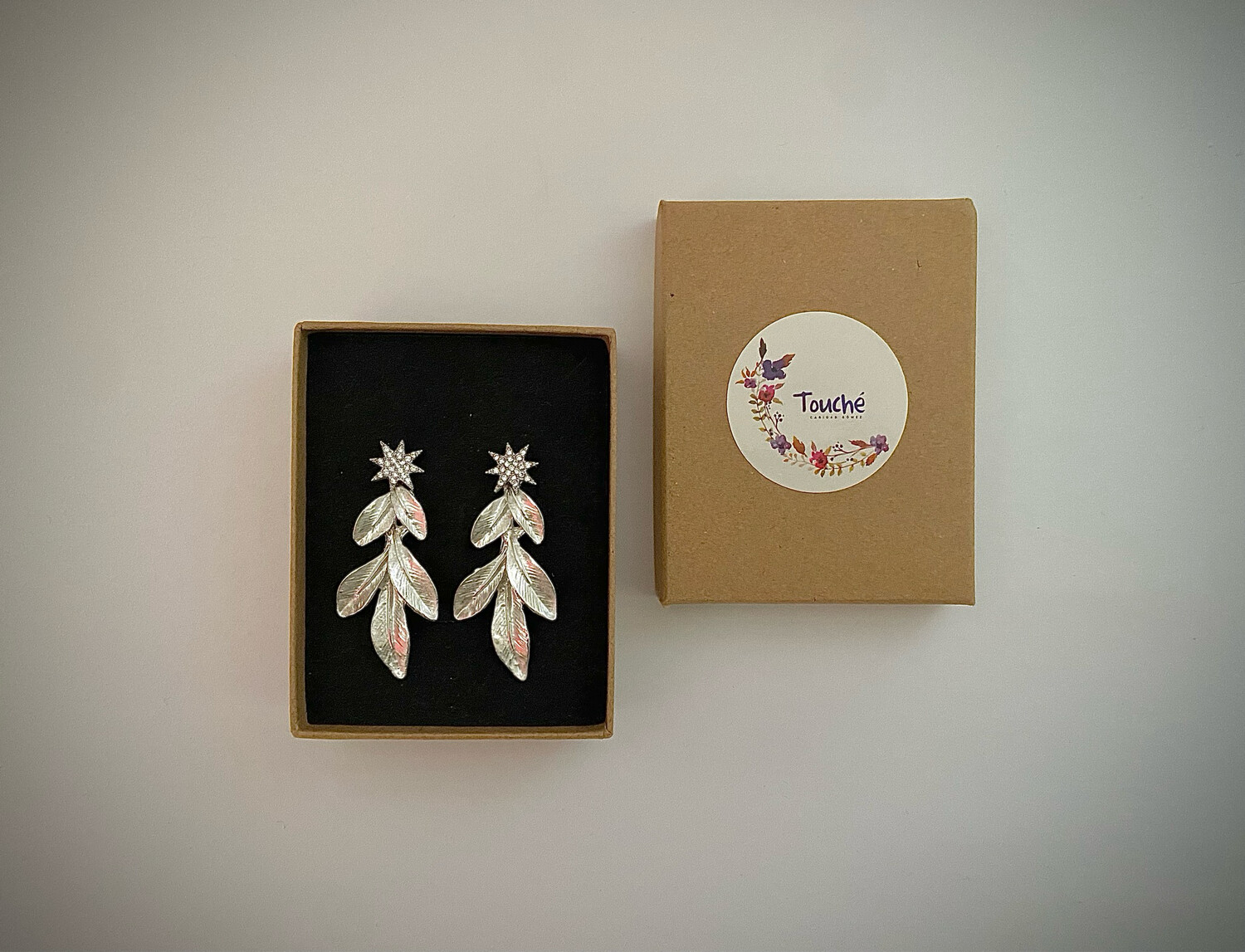 Pendientes con forma de estrella de unos 4 cm de largo y 1 cm de ancho en tonalidad plateada. Compuestos por estrella con pequeños cristales y una hoja en plata clara.

Son desmontables, se pueden usar sólo las estrellas o las estrellas y el colgante de hojas.