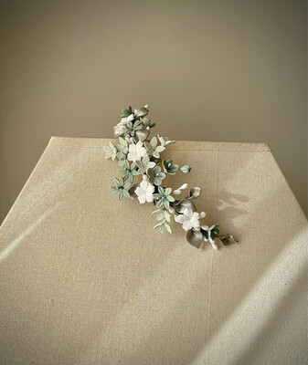 Tocado de porcelana con flores en diferentes tonos de verde agua y blanco y hojas en tono plata.